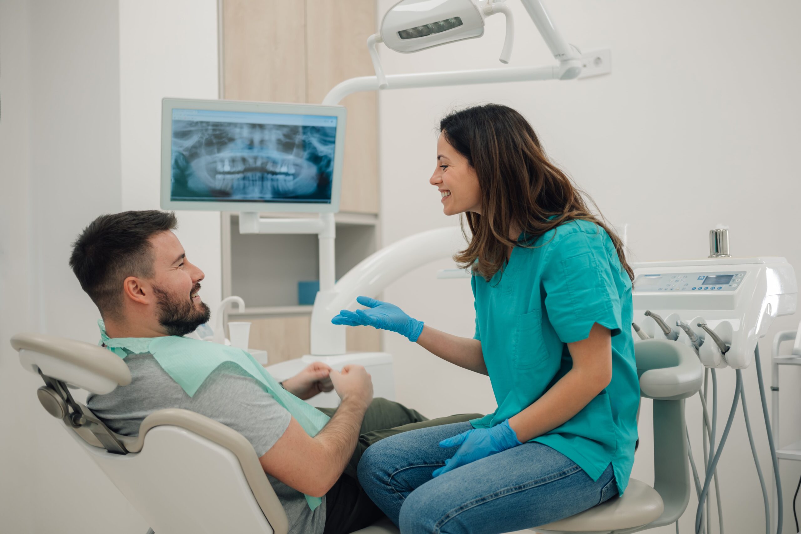 Female dentist showing dental x ray to patient in modern clinic