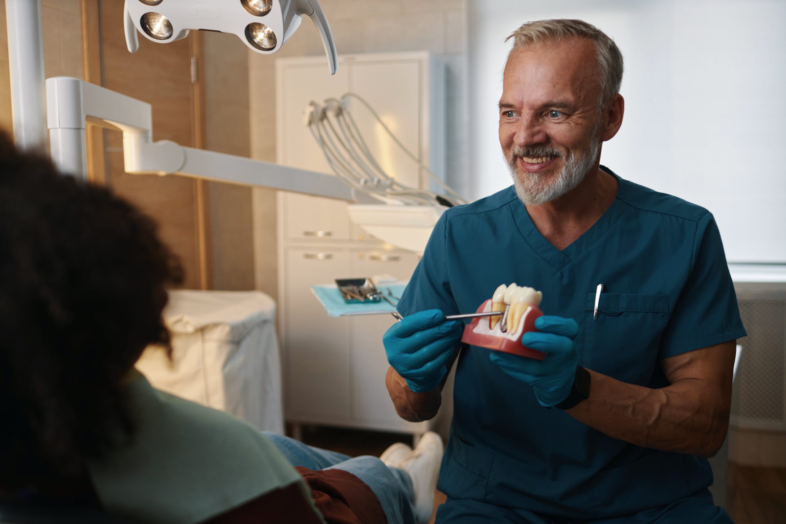 Smiling Dentist Explaining Procedure Using Dental Model
