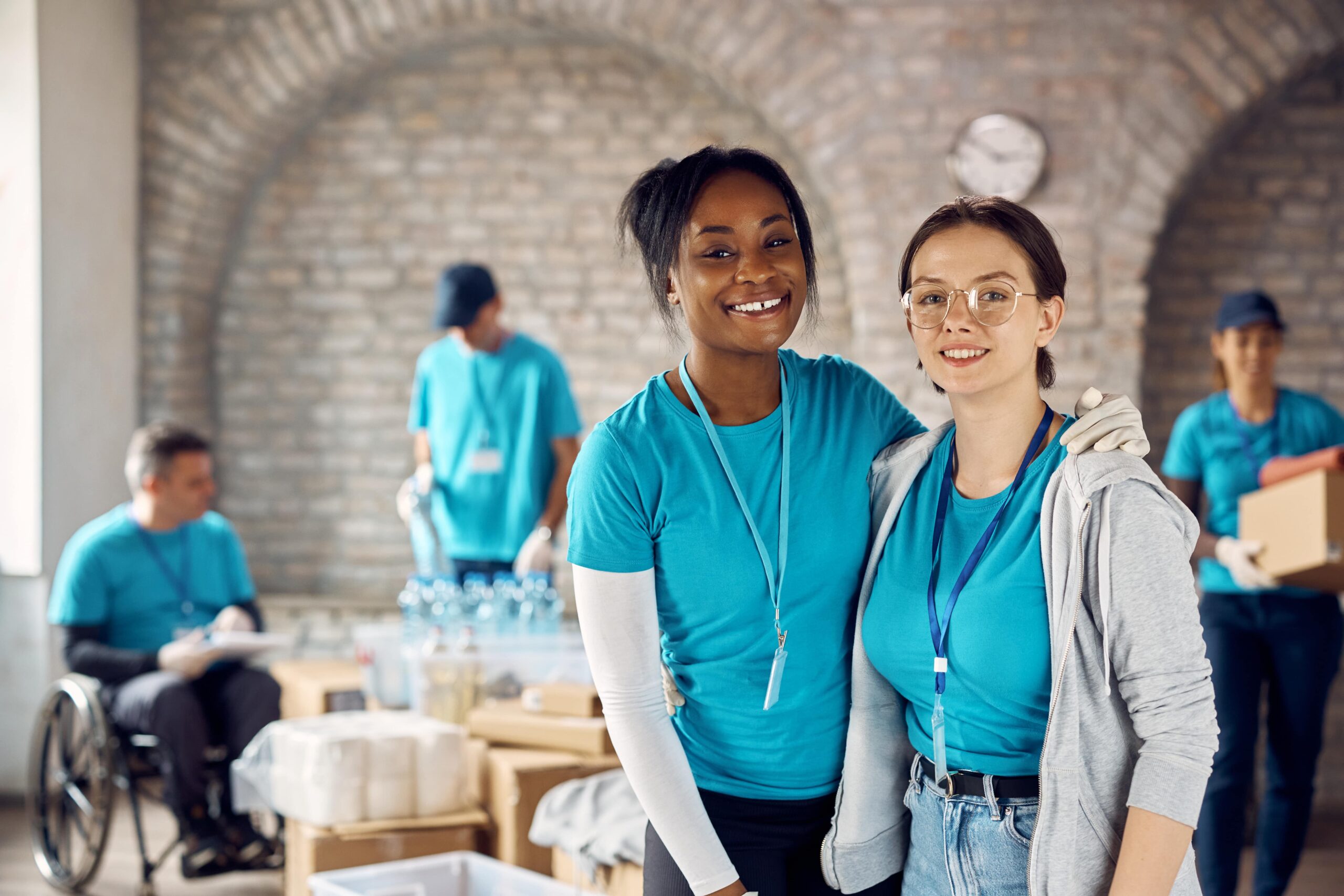 Young female volunteers working at donation center and looking at camera.