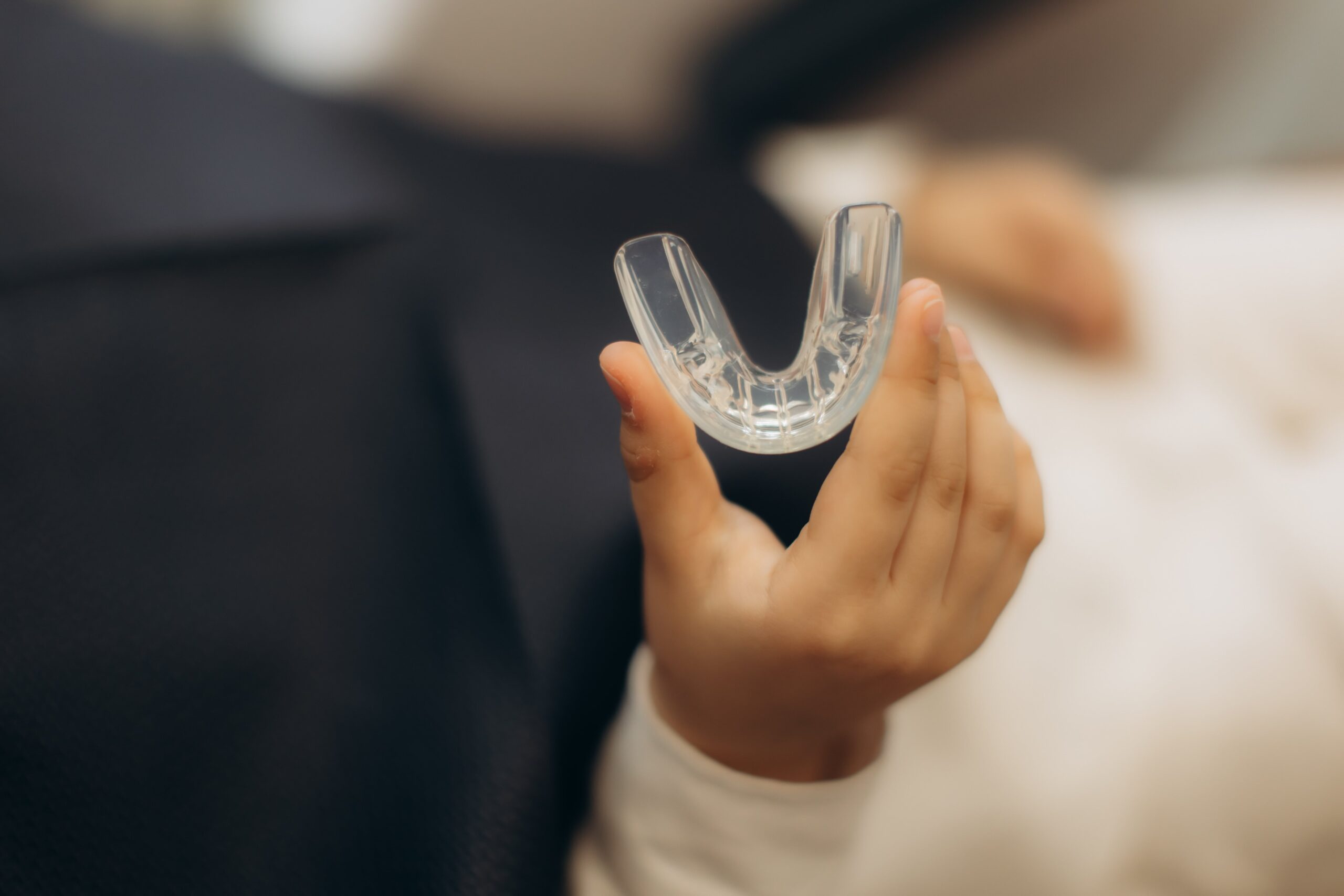 Patient holding transparent dental guard for teeth protection.