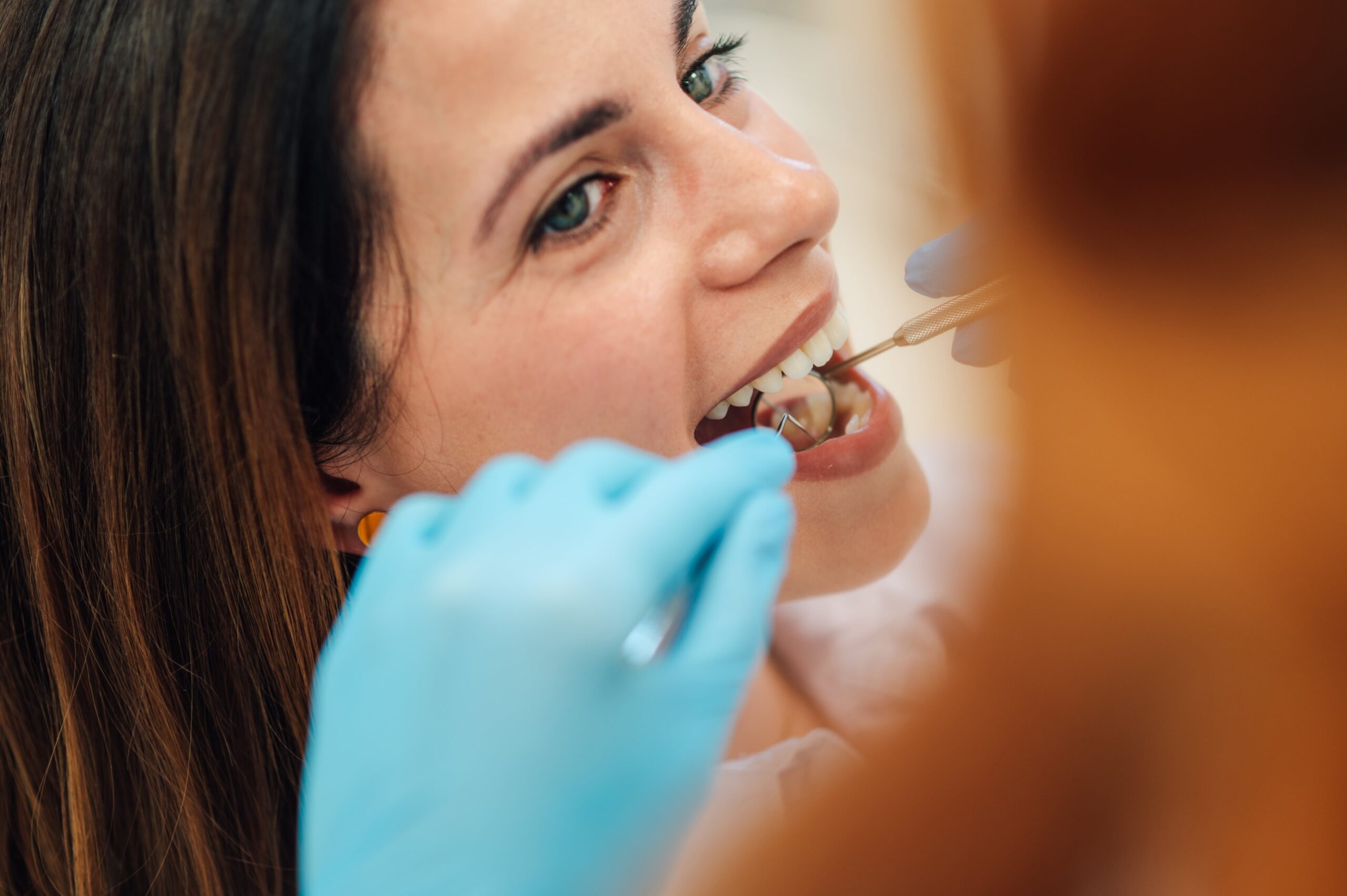 Dentist using dental probe and mirror examining patient's teeth