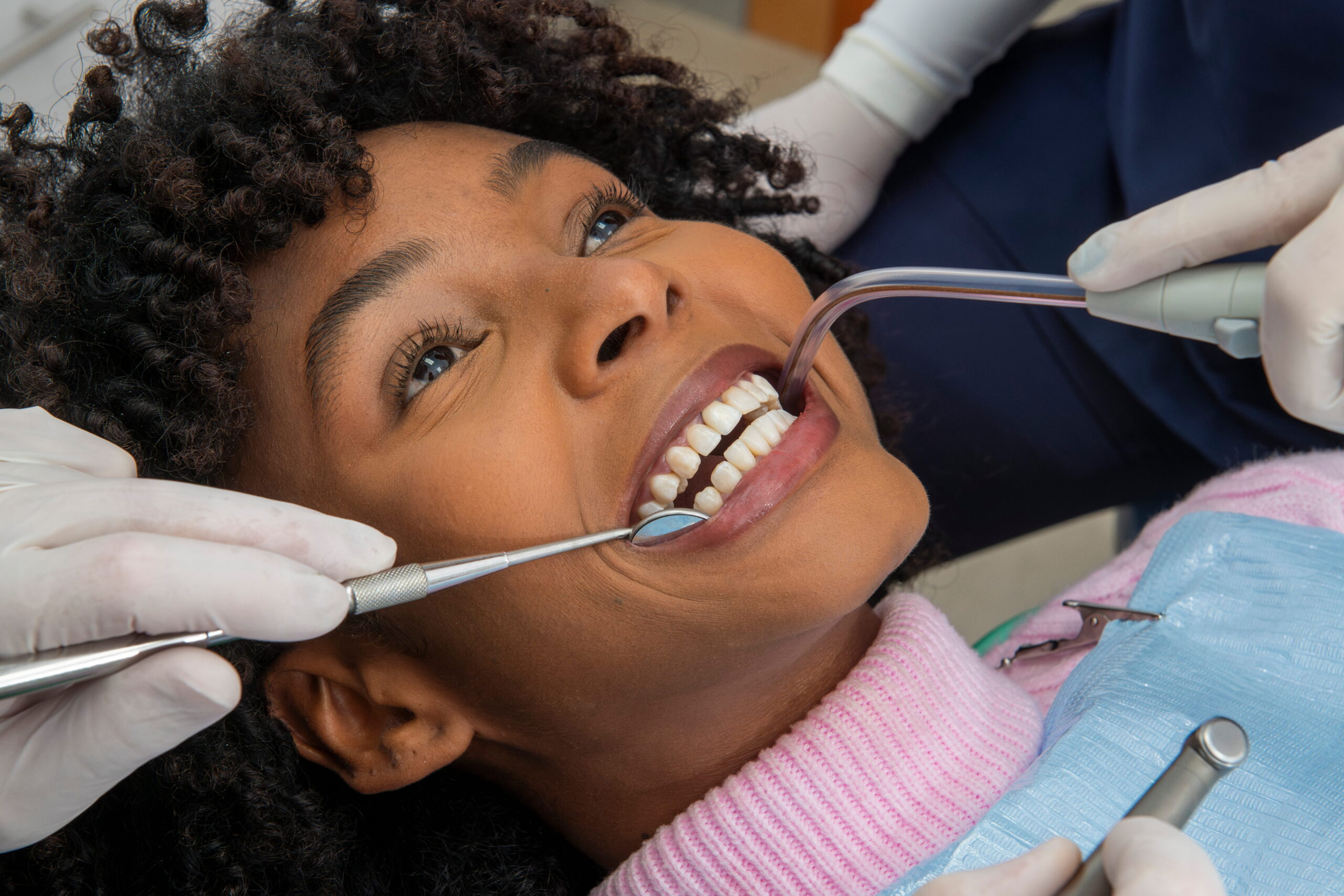 Female patient undergoing dental check up, receiving professional teeth cleaning at clinic